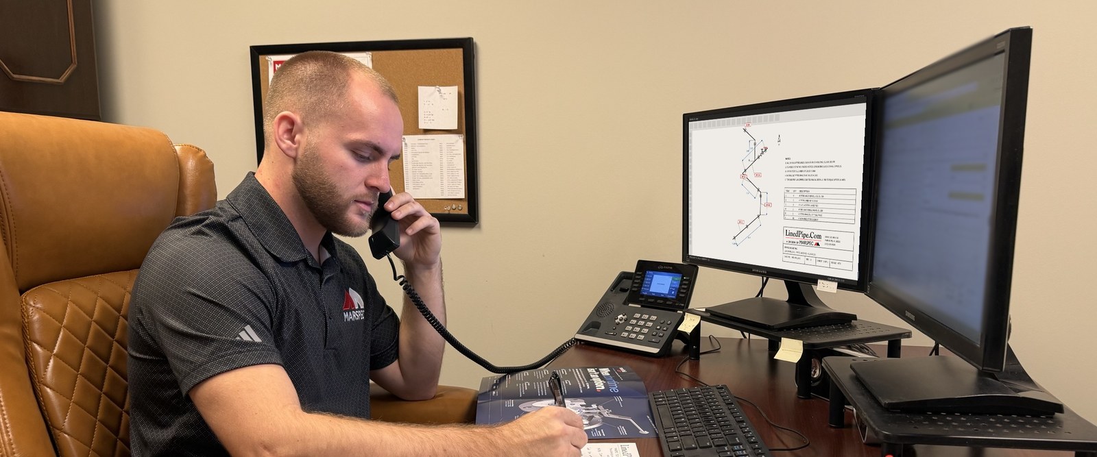 A Marspec team member taking a call at his desk, LinedPipe.Com order pad in front of him