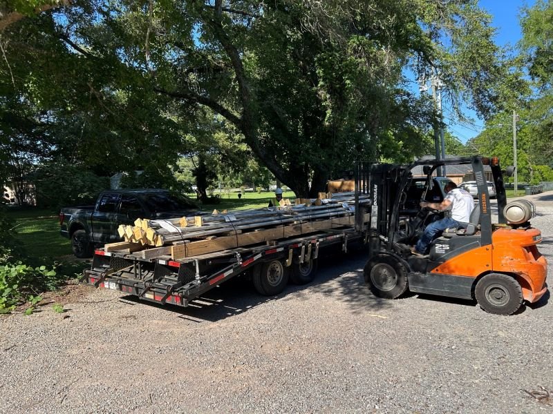 Forklift loading a flatbed trailer with a customer's order of lined pipe spools outside the Marspec shop