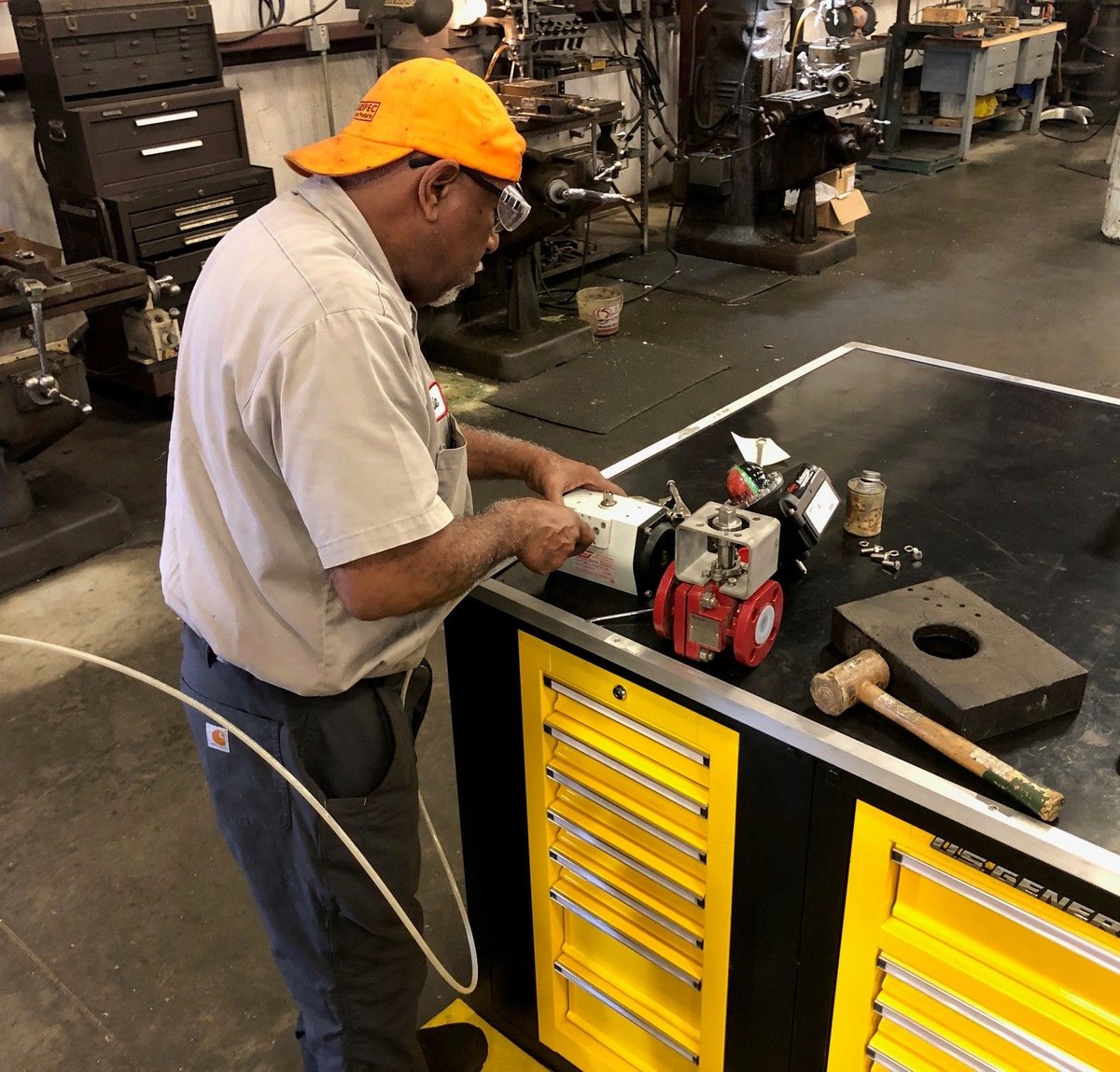 A technician mounting an actuator on a lined ball valve at the bench