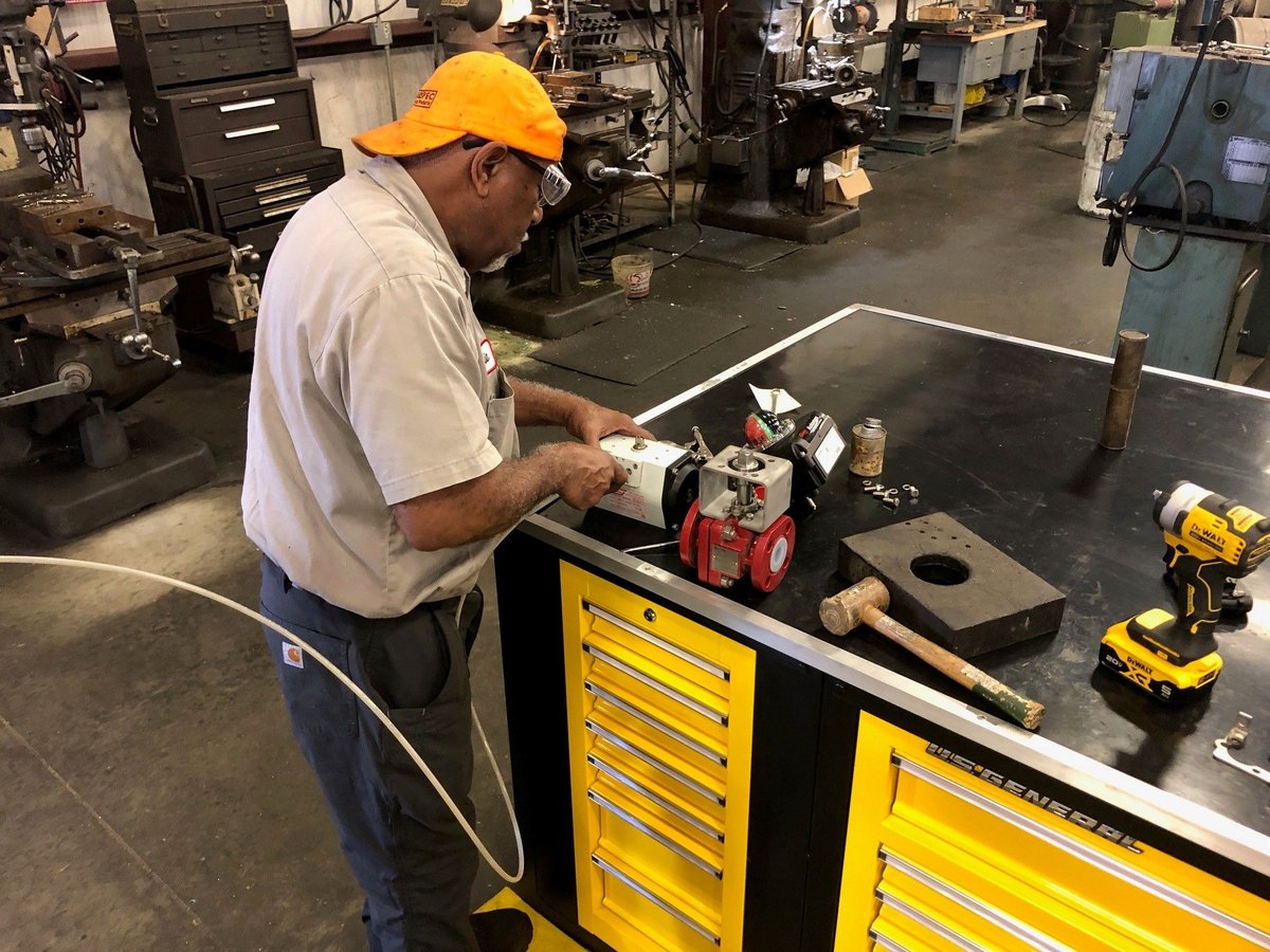 A Marspec technician mounting a pneumatic actuator and positioner on a lined ball valve at the shop bench